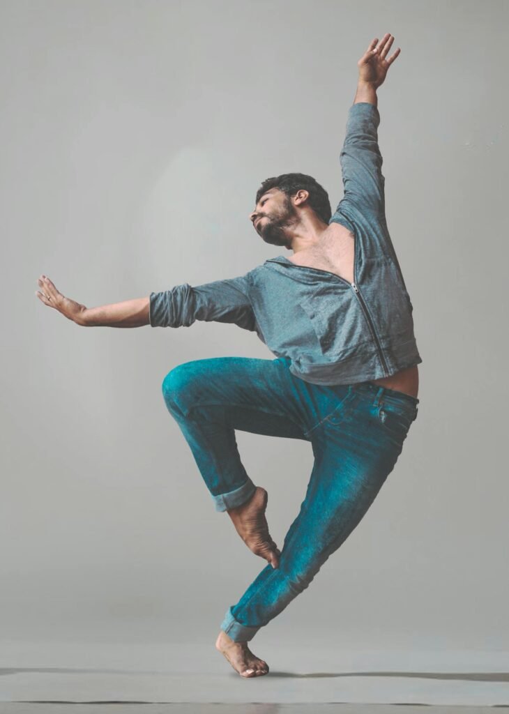 A male dancer strikes a dynamic pose in a studio setting, showcasing contemporary dance style.