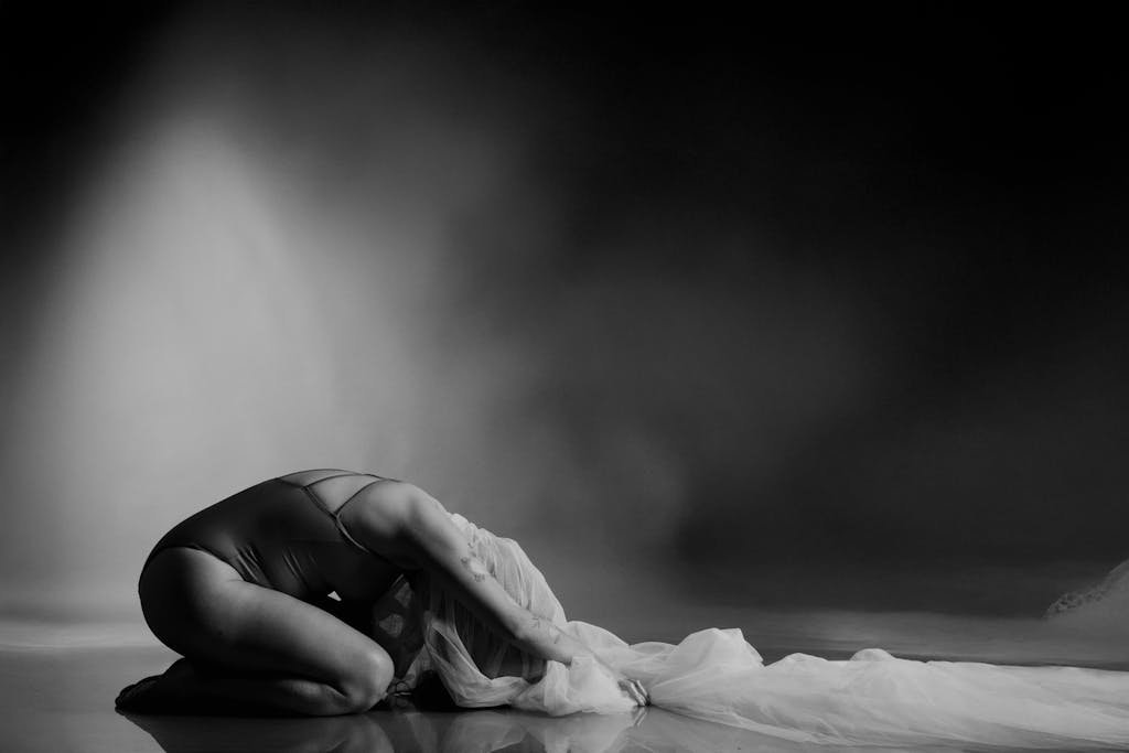 Black and white artistic photo of a dancer posed gracefully with flowing fabric.