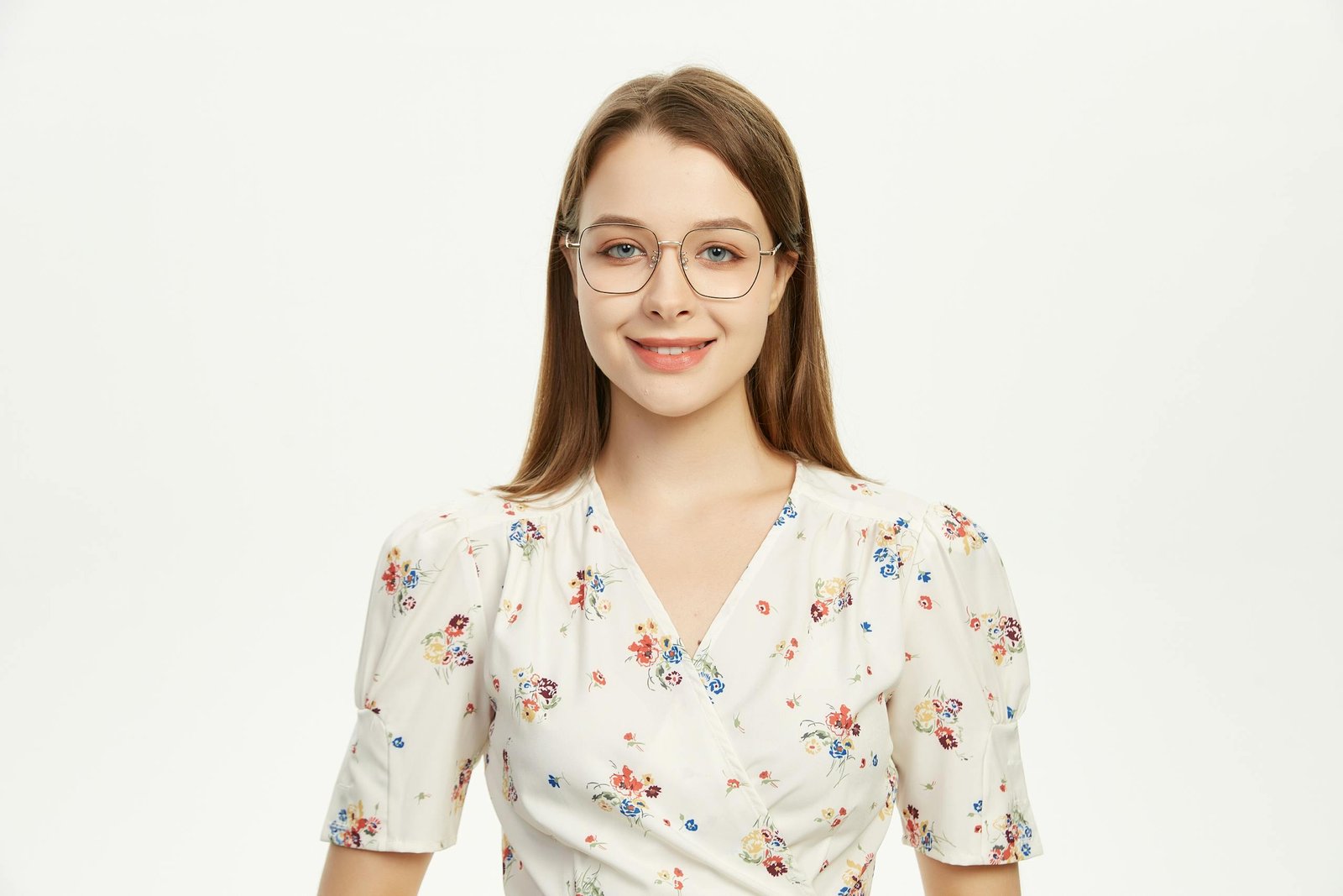 Young woman wearing glasses smiling in a floral outfit against a plain background.
